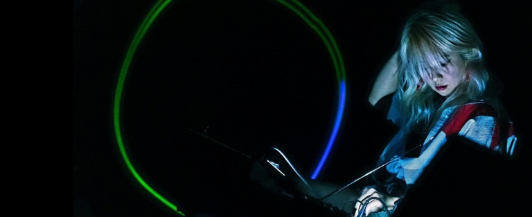 Person drejer på knapper på mixer board i mørkt lokale