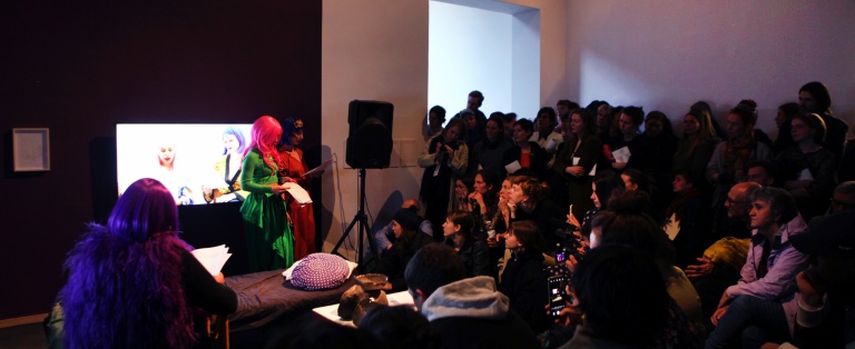 publikum betragter personer i kostume i kunstinstallation i forbindelse med performance