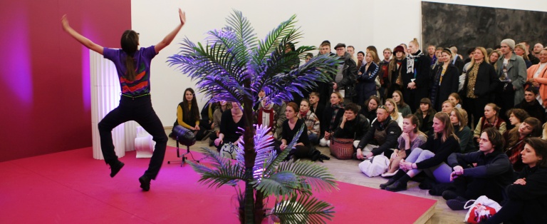 Et publikum betragter person i kunstinstallation i forbindelse med performance