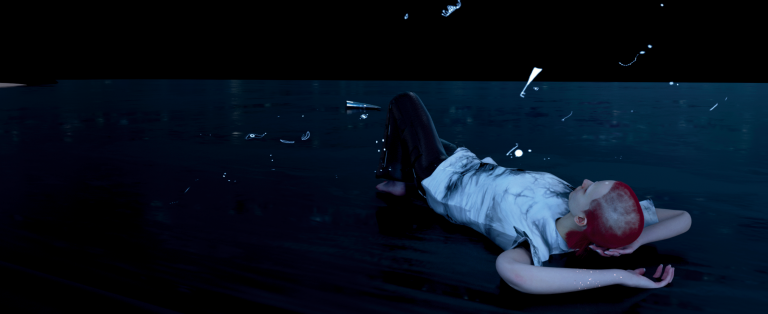 Stilbillede der viser en liggende figur i mørke omgivelser fra videoværk