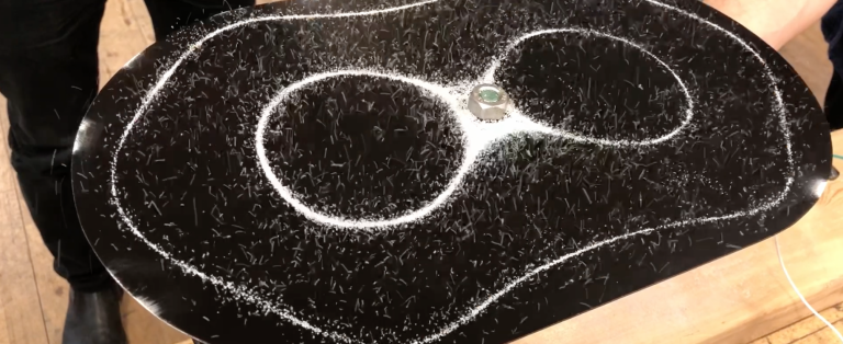 Små, hvide spåner samler sig i cirkelformationer på sort, oval plade