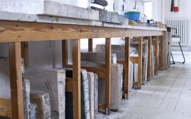 Opbevaring af litografiske sten under bord med materialer og redskaber