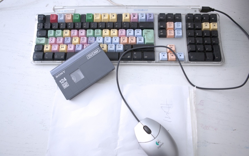 Tastatur med farvede taster, et bånd og computermus på et bord