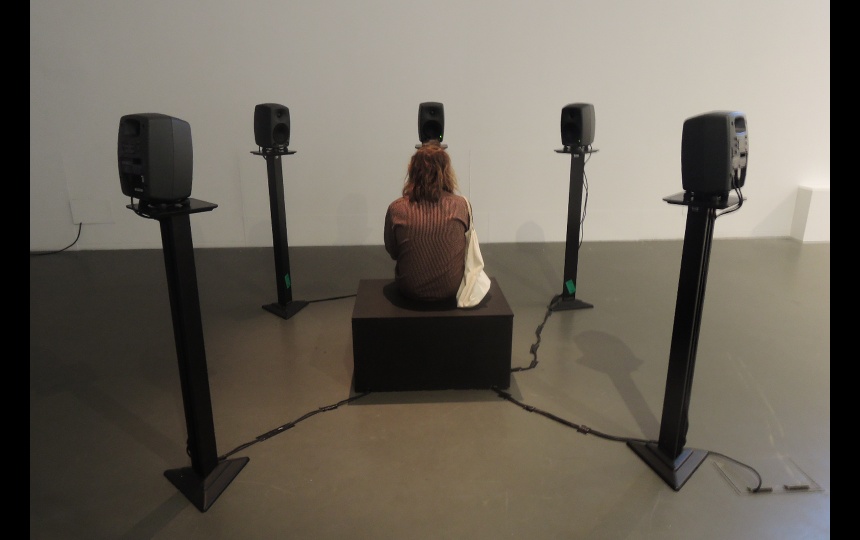 Person sidder på kasse omgivet af fem højtalere