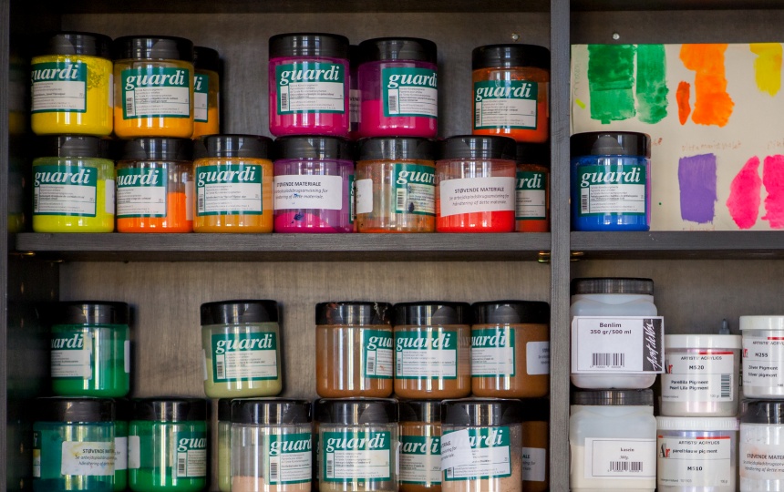 Stablede gennemsigtige bøtter med farve på hylder