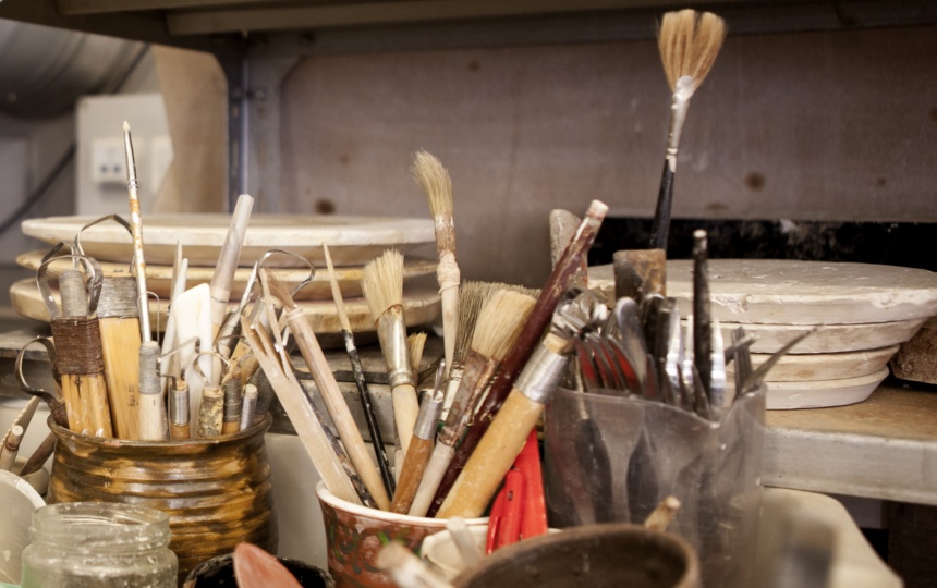 Pensler og andre redskaber i krus foran stablede gipsplader