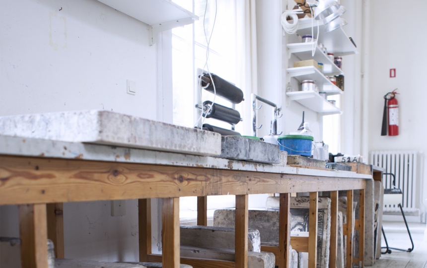 Opbevaring af litografiske sten under bord med materialer og redskaber