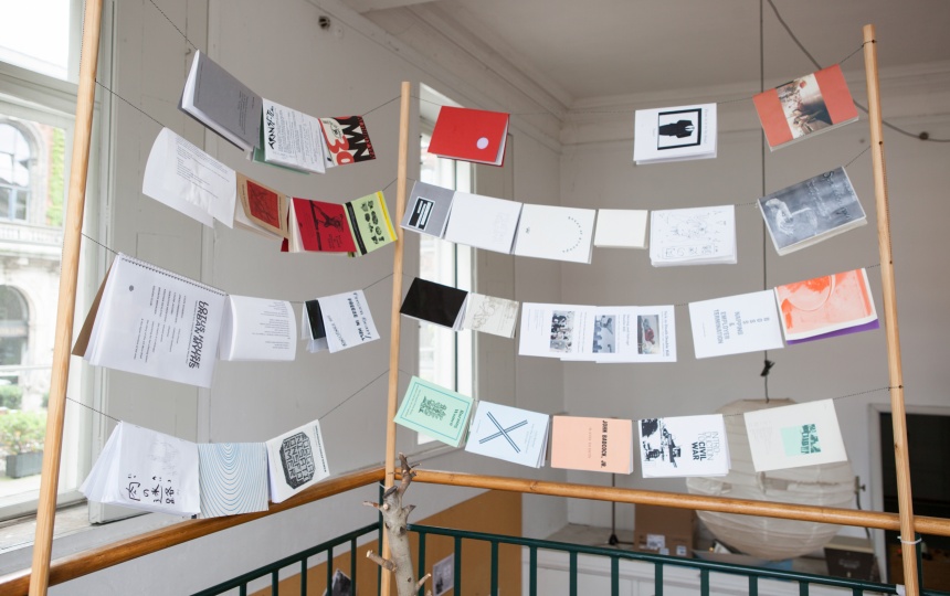 Bøger og andre papirpublikationer, der hænger på snore, som er spændt ud mellem træpæle