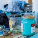 Malertuber, klude og gamle syltetøjsglas med væske og maling